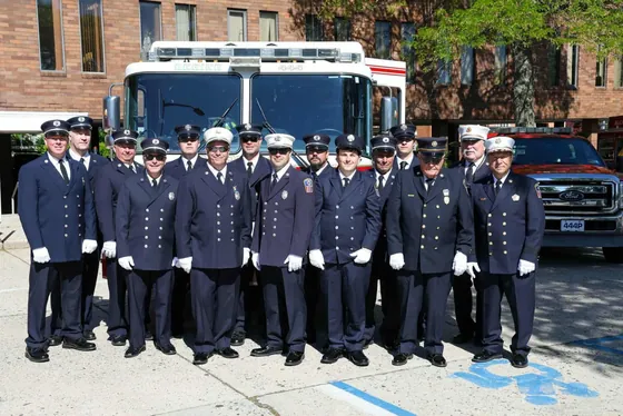 The members of Woodland Engine Company No. 4 in dress uniform, lined up in front of Engine 444 outside the firehouse